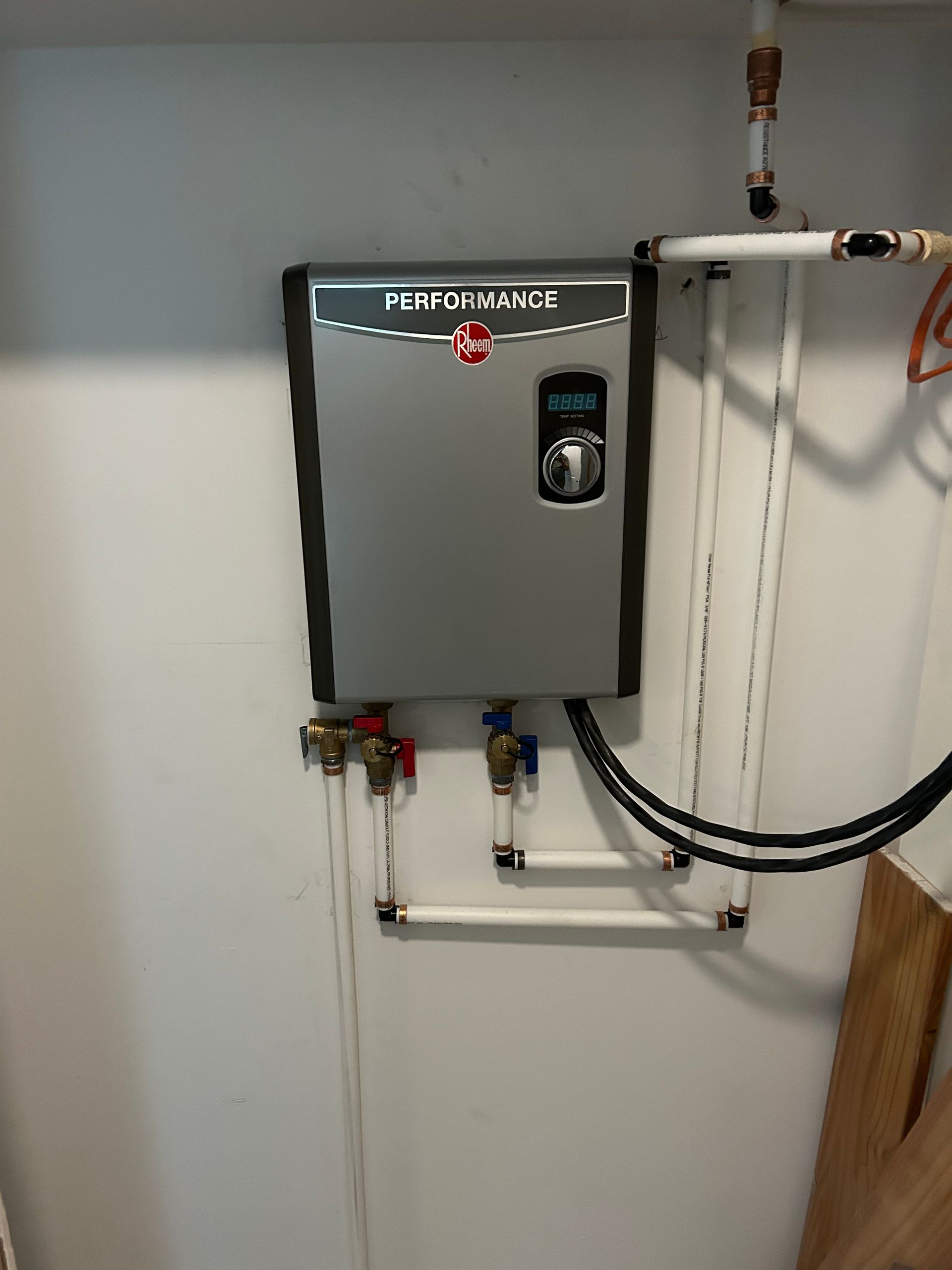 Aqua Plumbing Pros | A water heater is hanging on a white wall.