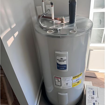 Aqua Plumbing Pros | A white water heater is sitting in a corner of a room