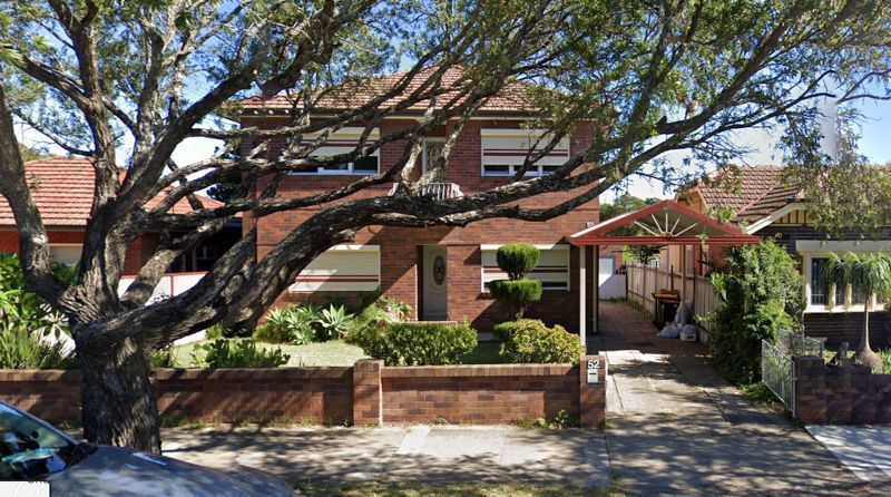 A large brick house with a tree in front of it.