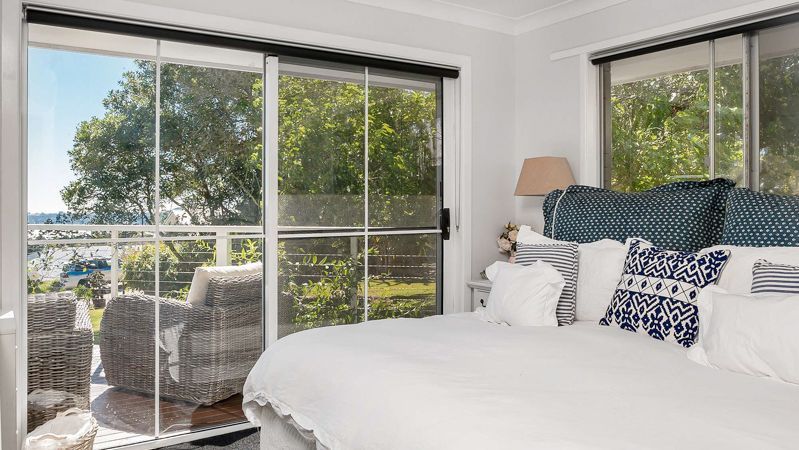 A bedroom with a large bed and sliding glass doors leading to a balcony.