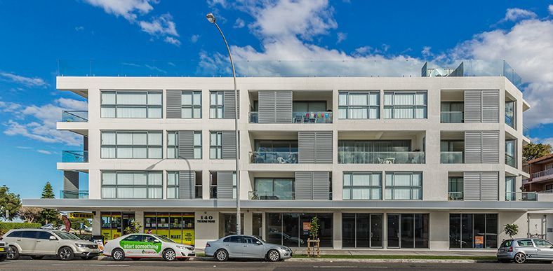 A large white apartment building with cars parked in front of it.