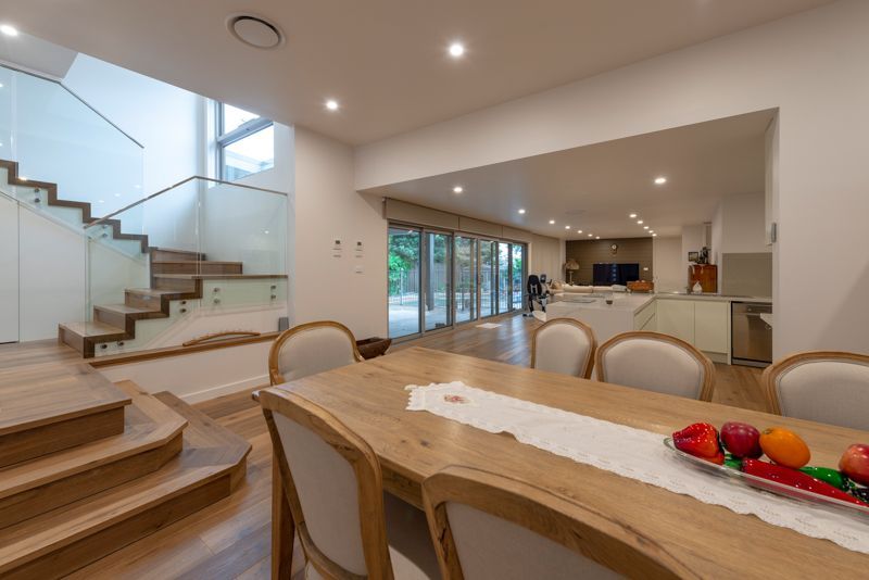 A dining room with a wooden table and chairs and a glass staircase.