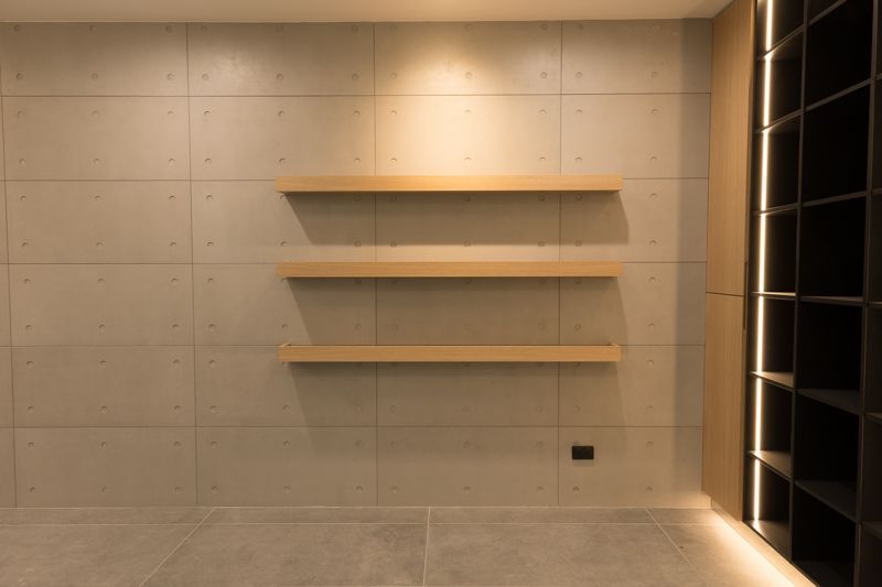 A room with a concrete wall and wooden shelves.