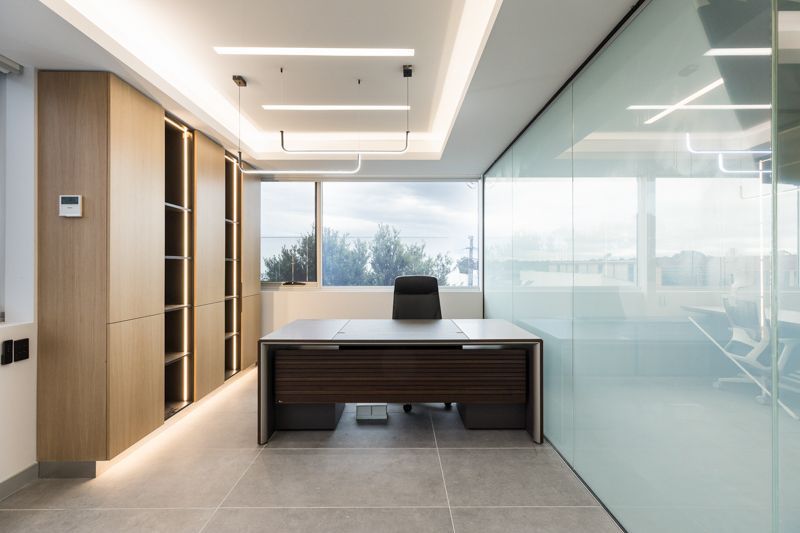 An empty office with a desk and chair in front of a window.