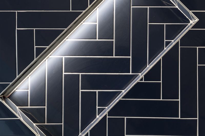 A close up of a black tile wall with a light shining through it.
