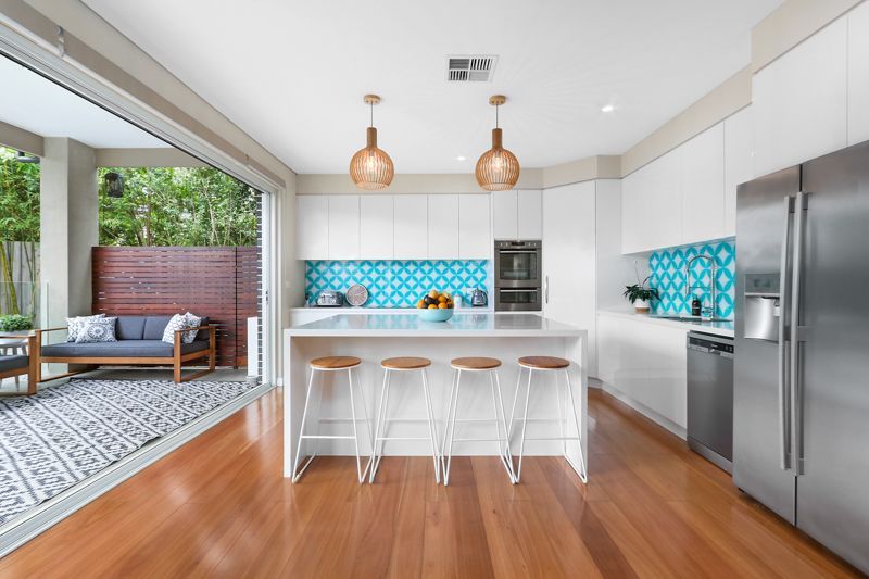 A kitchen with white cabinets , stainless steel appliances , wooden floors and a large island.