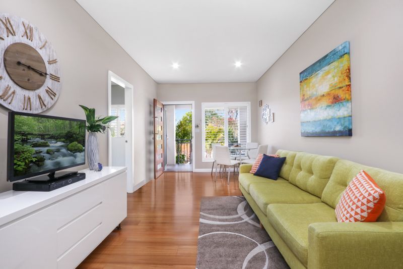 A living room with a green couch and a clock on the wall.