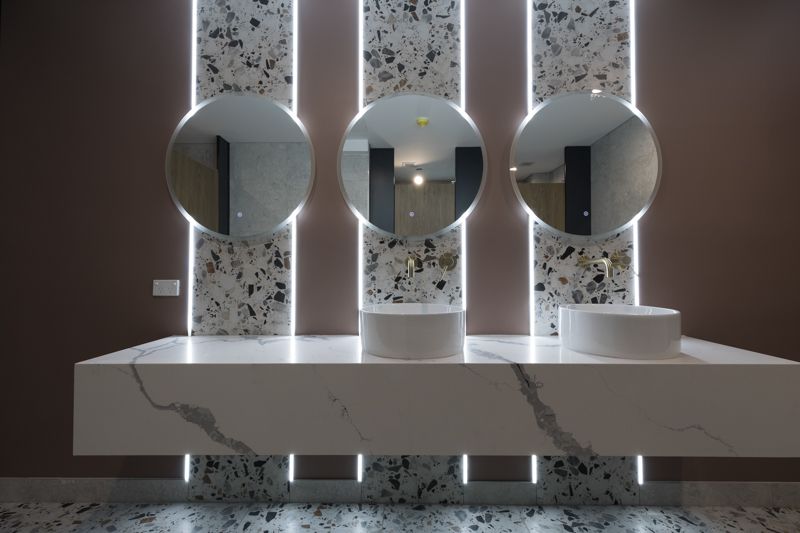 A bathroom with three sinks and three mirrors on the wall.