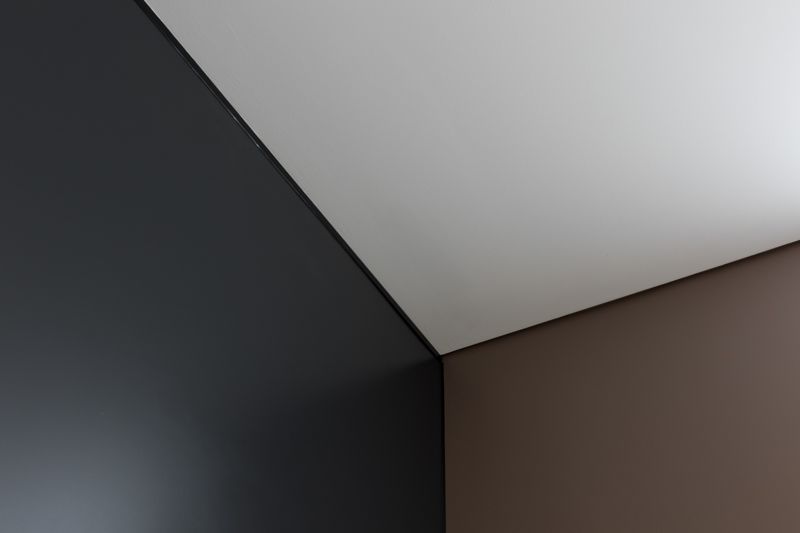 A black , white and brown wall with a white ceiling.