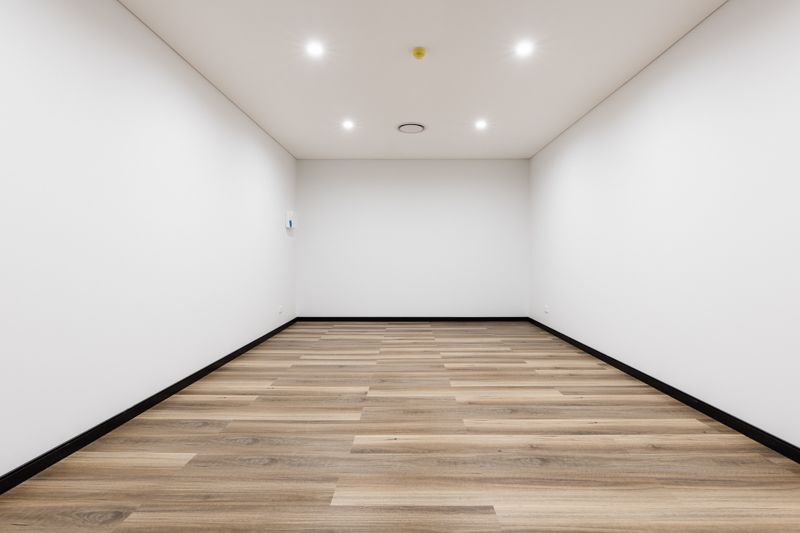 An empty room with a wooden floor and white walls.