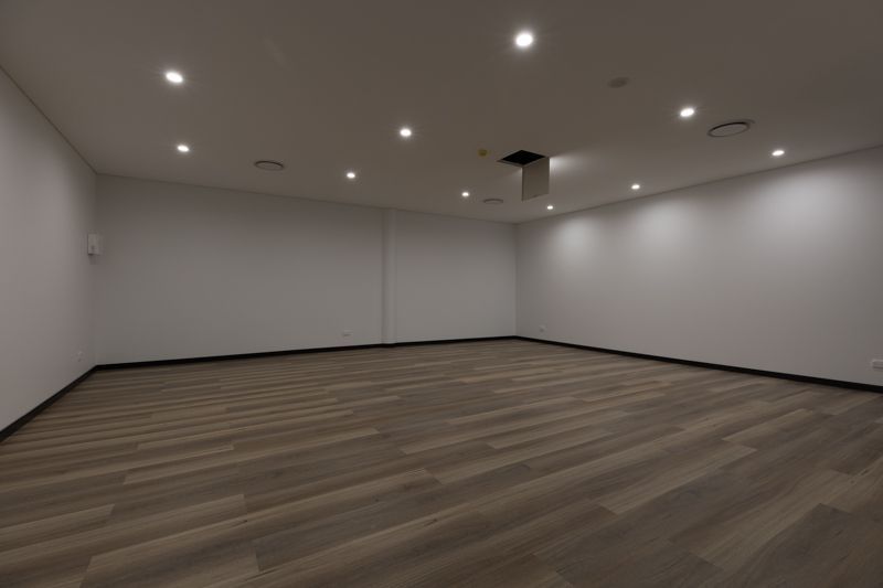 An empty room with a wooden floor and white walls
