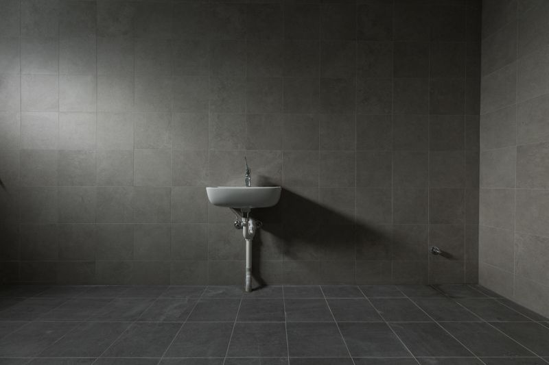 An empty bathroom with a sink on the wall.