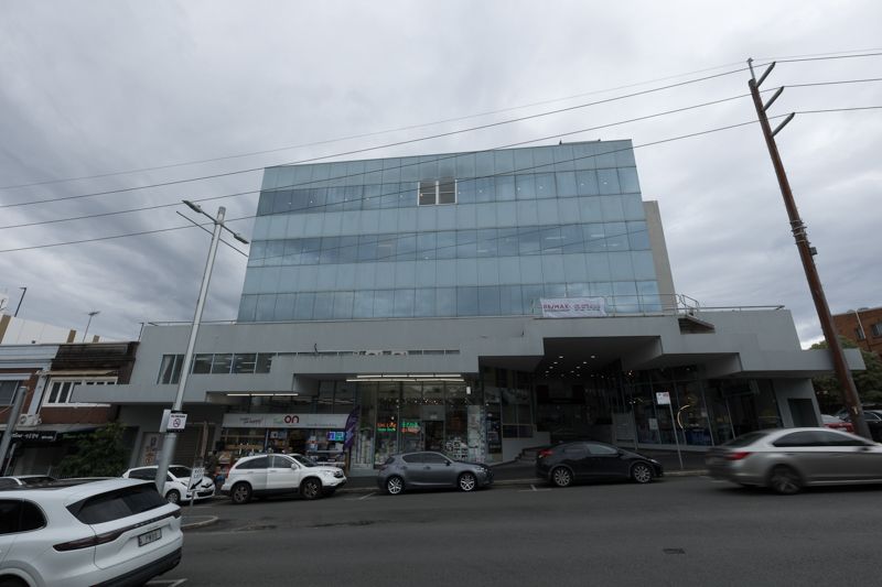 A large building with a lot of windows and cars parked in front of it.