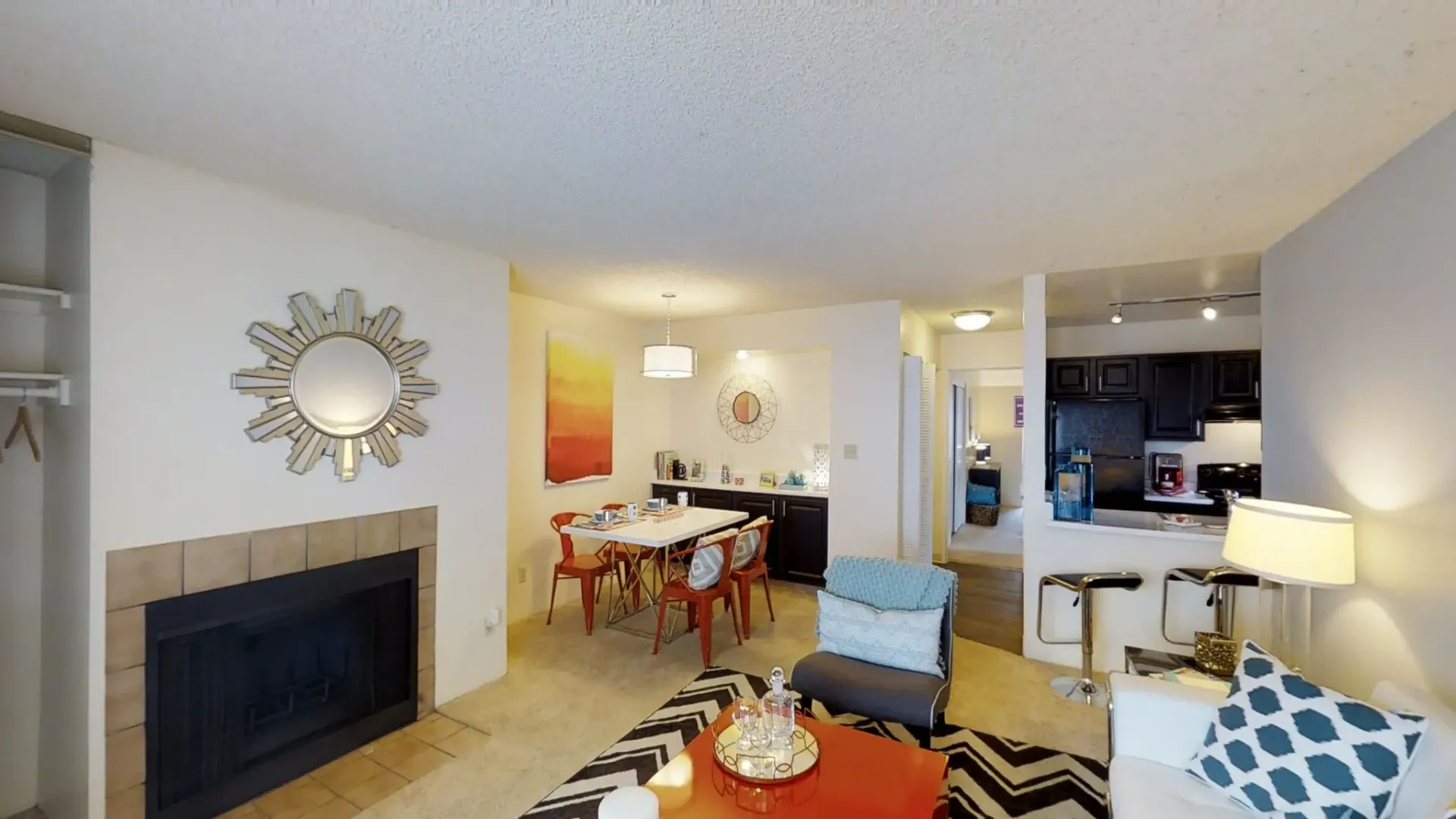 Living room and dining area of an apartment with fireplace and kitchen view.