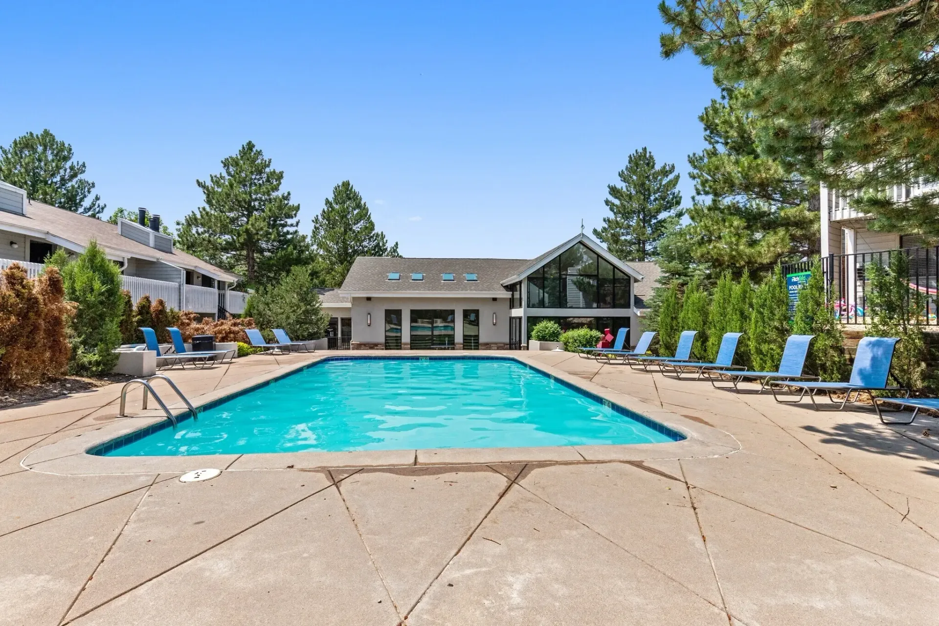 Swimming pool with lounge chairs and building in the background.
