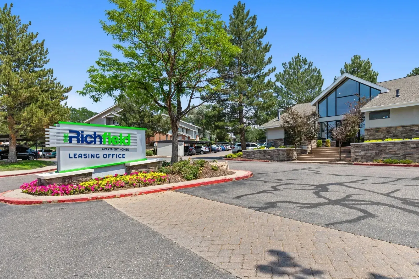 Richland retirement community entrance with sign, flower bed, and building under a blue sky