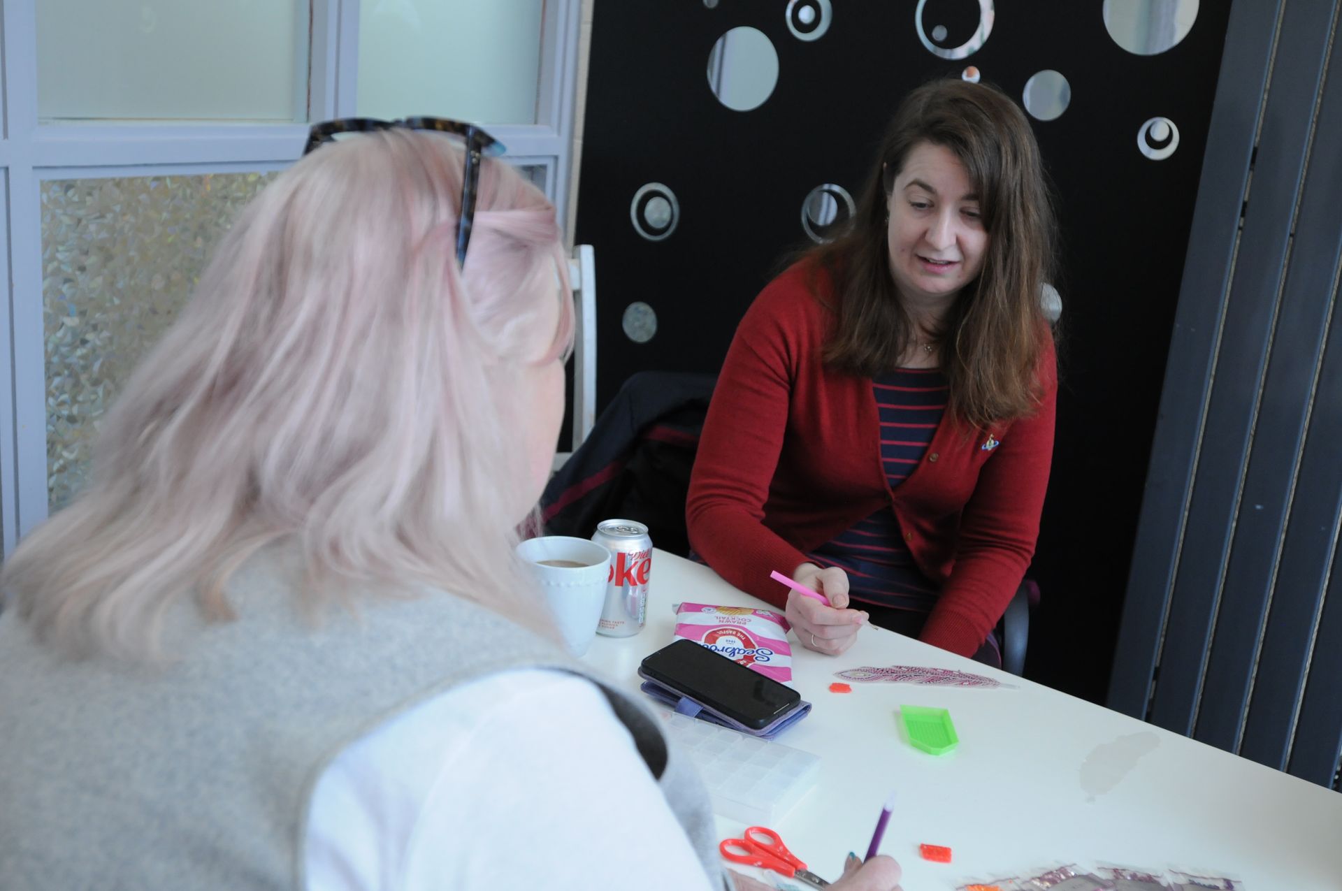 Two women are sitting at a table talking to each other.
