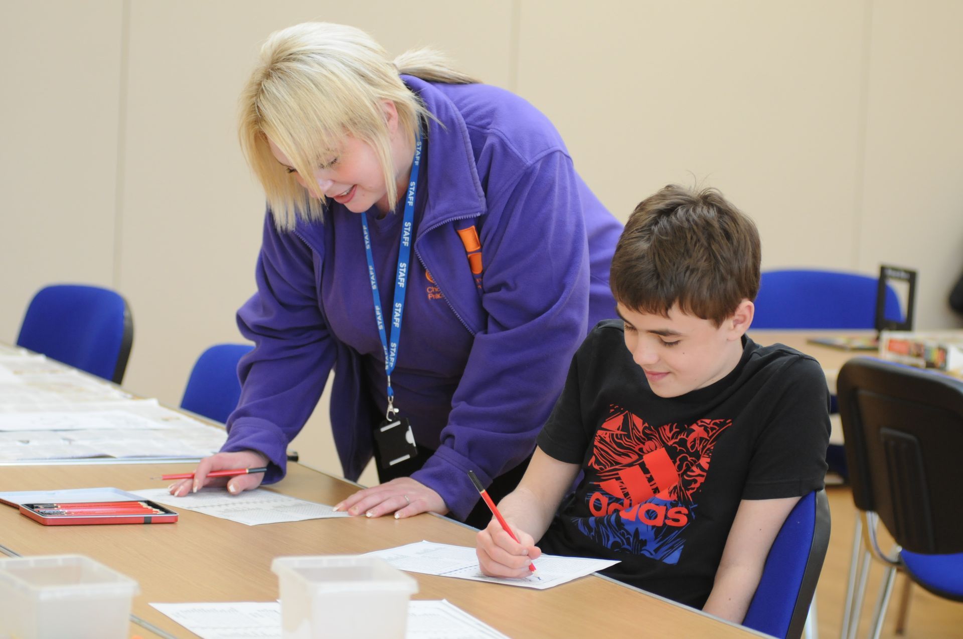 A woman in a purple jacket is helping a boy with his homework