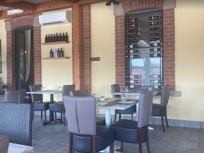 Due calici da vino, uno bianco e uno rosso, davanti a bottiglie di vino su un tavolo di legno.
