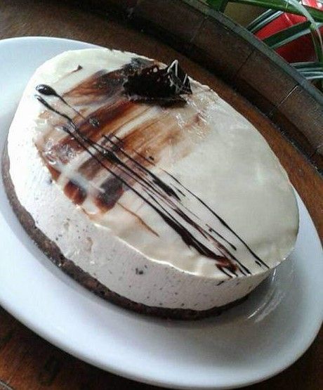 Dessert a forma di cupola ricoperto di cioccolato, servito su un piatto bianco.