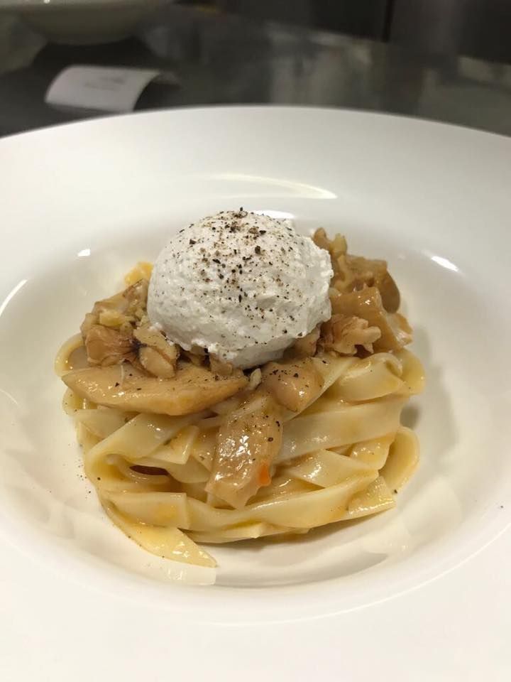 Pasta in una ciotola bianca condita con una cucchiaiata di ricotta e salsa al pepe.