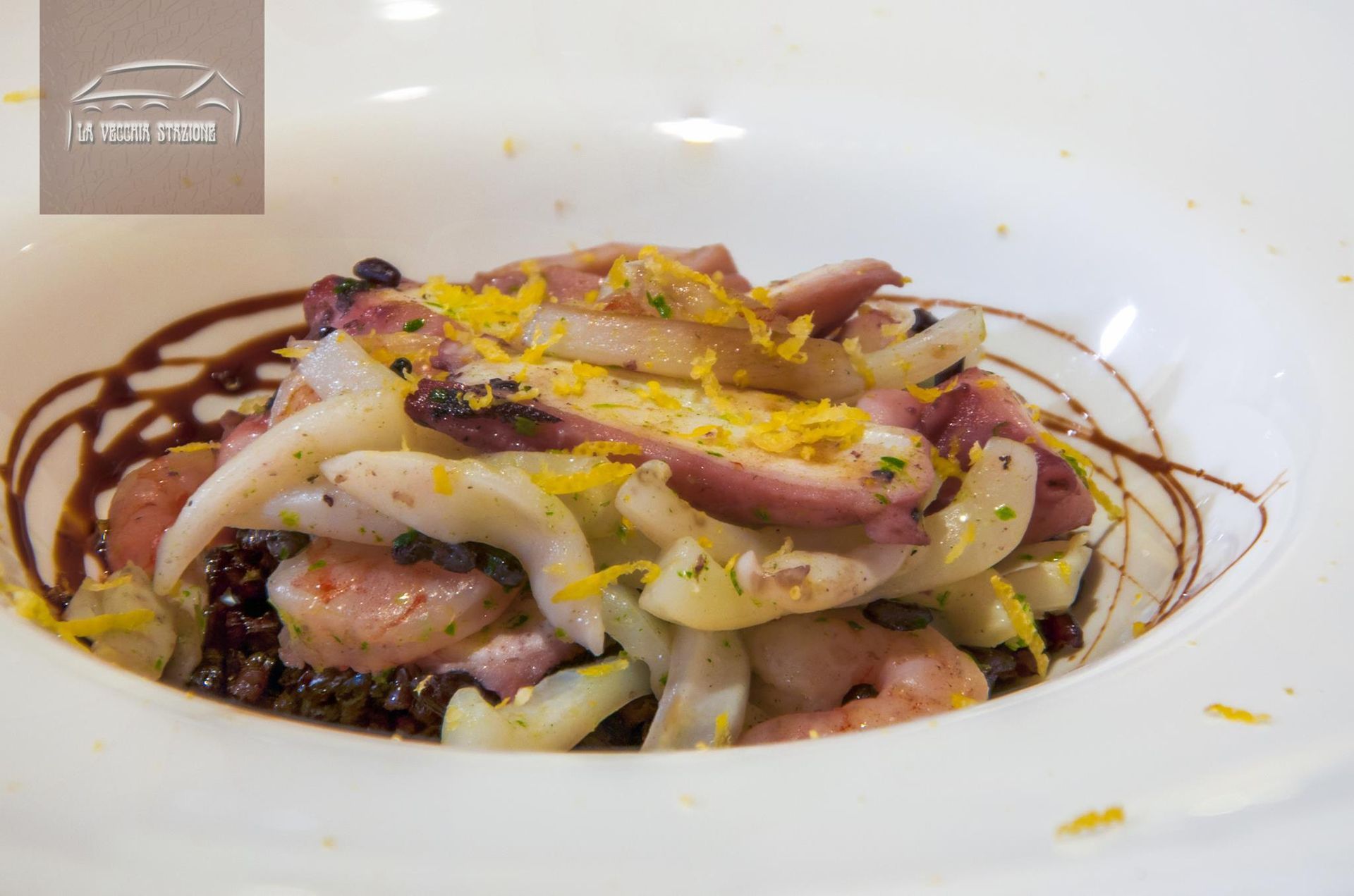Insalata di frutti di mare gourmet con guarnizione colorata in una ciotola bianca, condita con salsa scura.