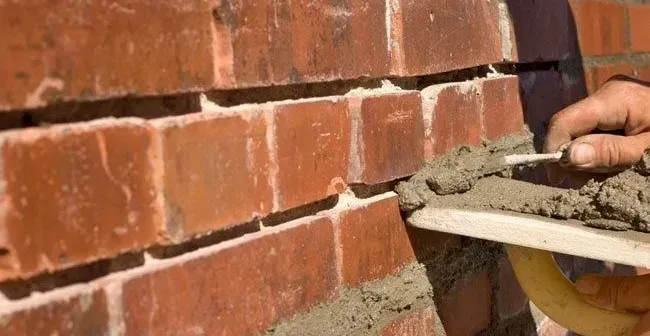 Mortar is being inserted between bricks on a tuckpointing and masonry repair job in Wichita, Kansas. 