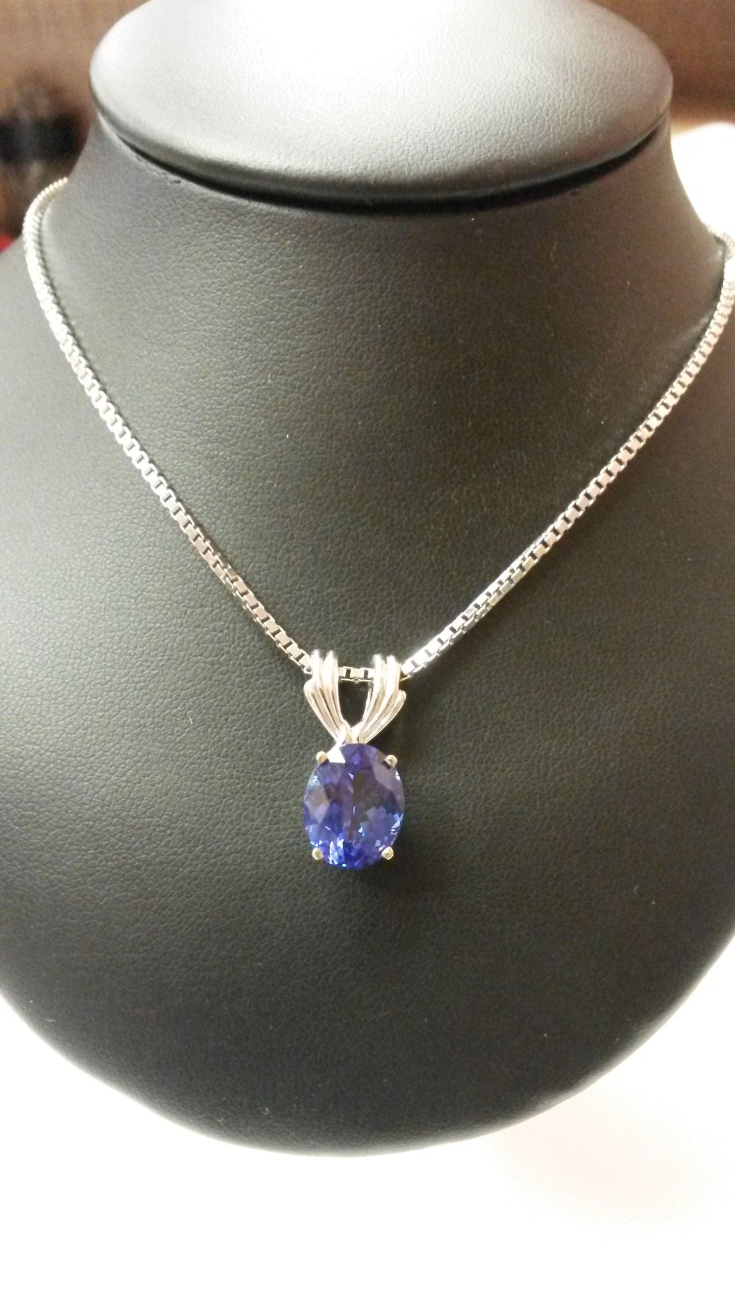 Blue gemstone pendant necklace on a black display bust