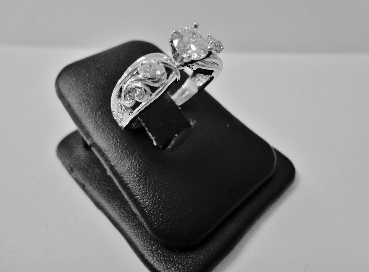 Silver ring with a floral design displayed on a black ring stand.