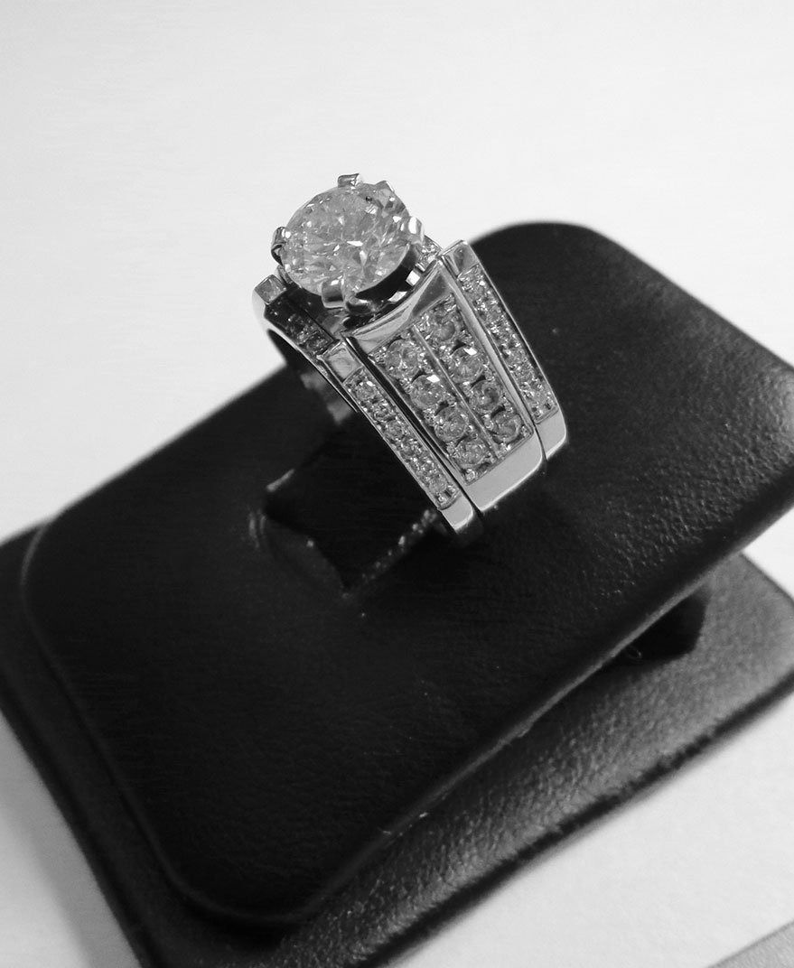 Diamond ring displayed on a black jewelry stand against a white background