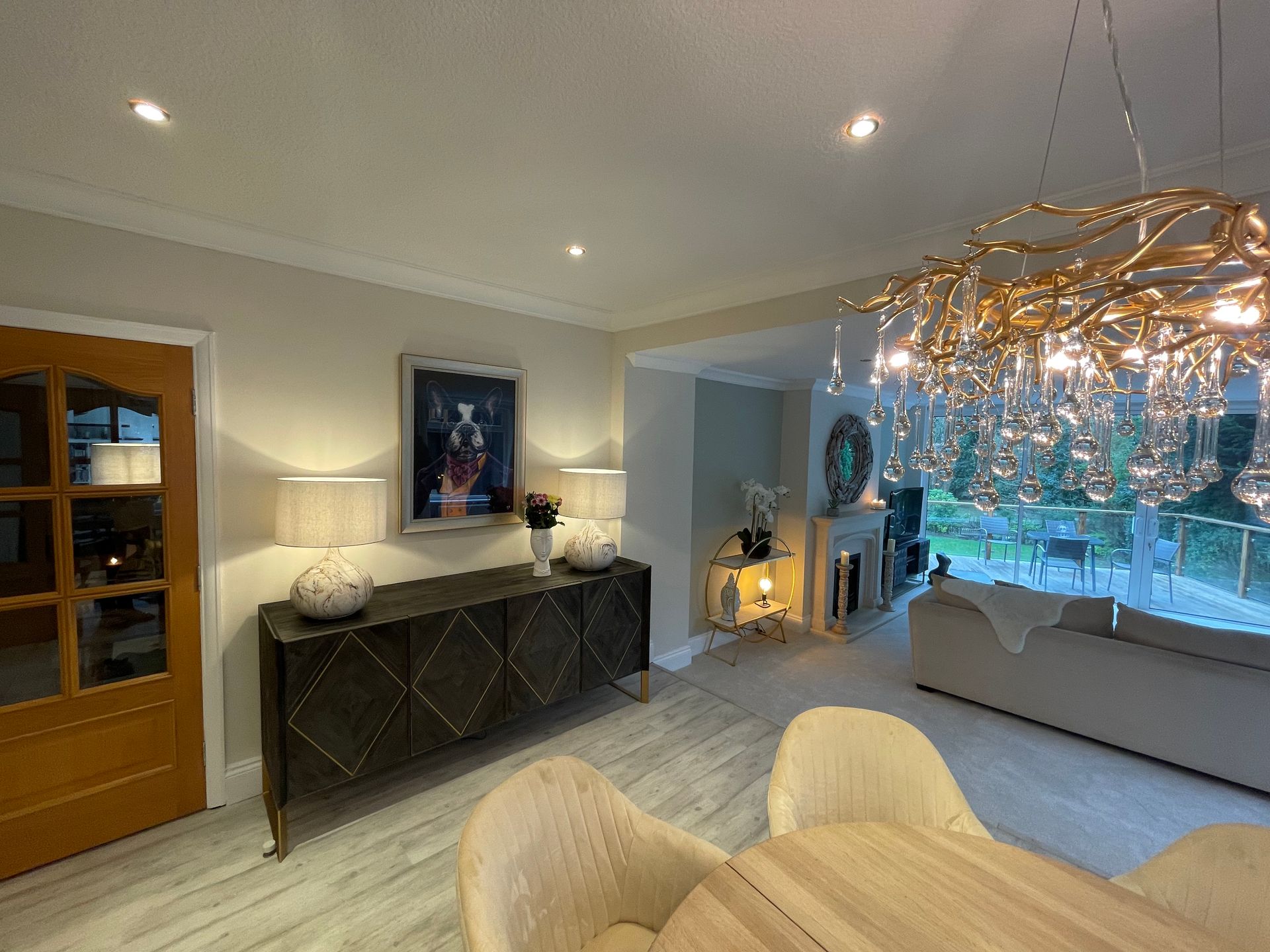 Chandelier above the dining table, with beautiful sideboard, lamps and artwork