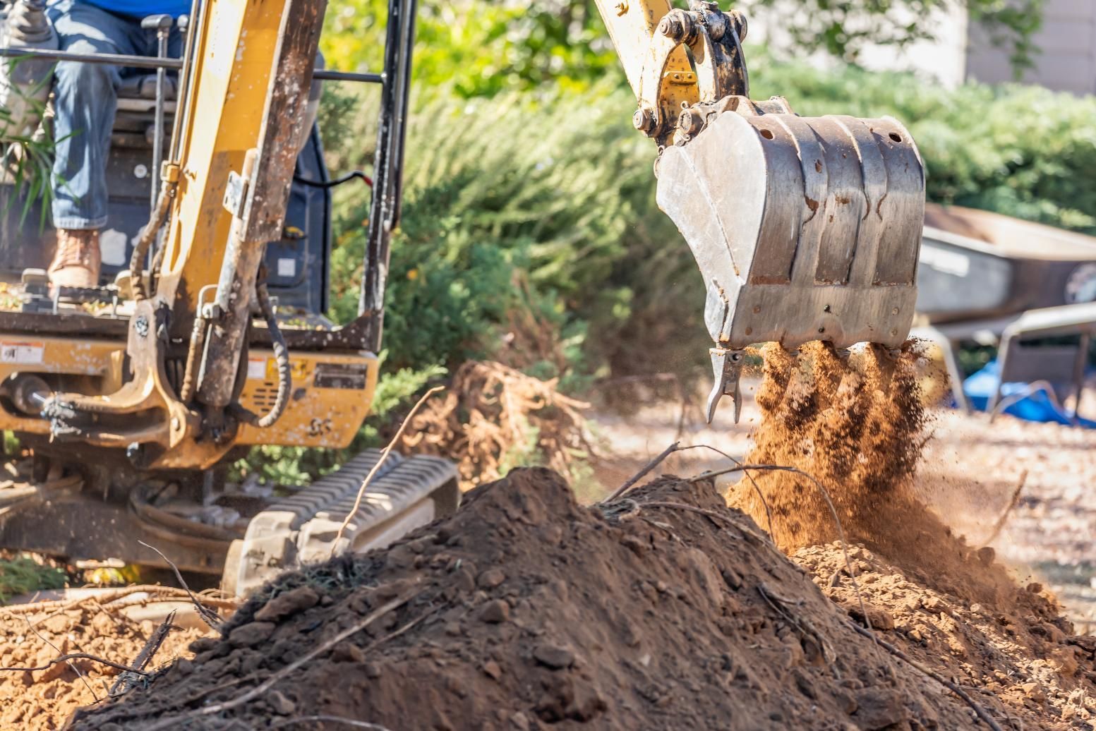 Excavator dumping dirt onto a soil pile at a construction site