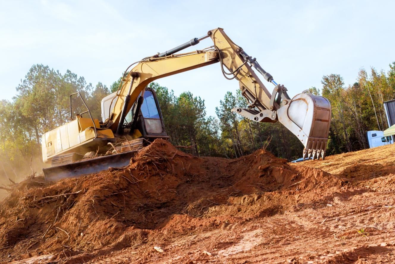Yellow excavator digging dirt on a muddy construction site with trees in the background