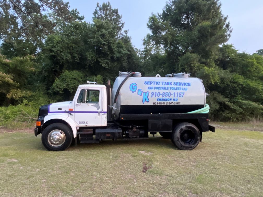 White water service truck parked on grass beside trees under a cloudy sky in Lumberton NC