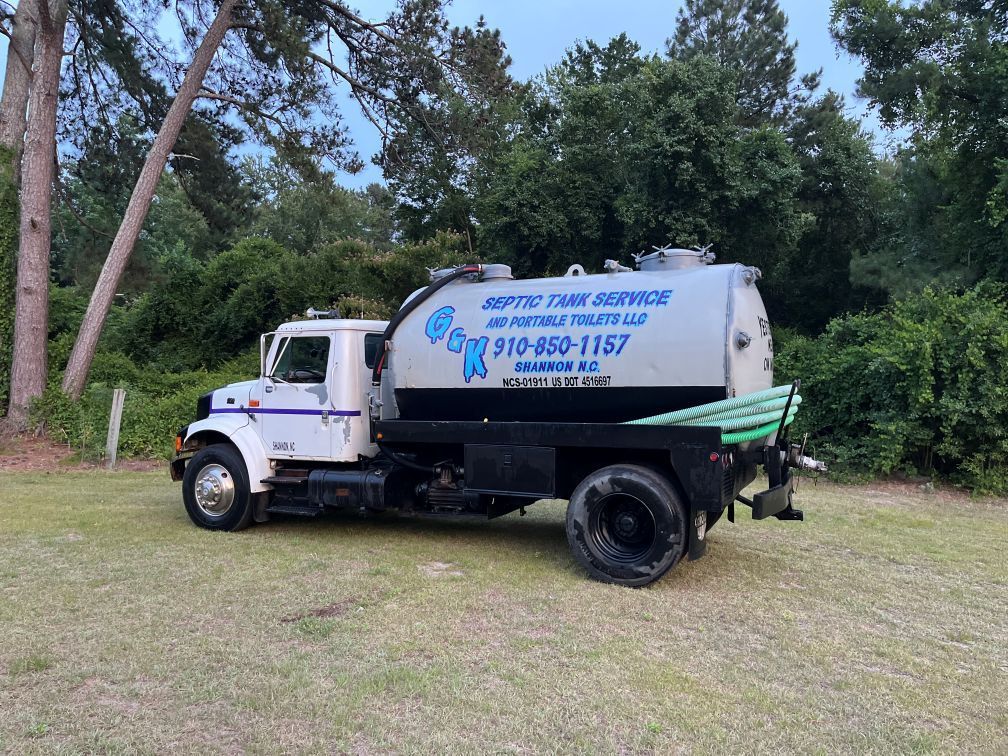 White utility truck with blue lettering parked on grass beside trees in Pinehurst NC