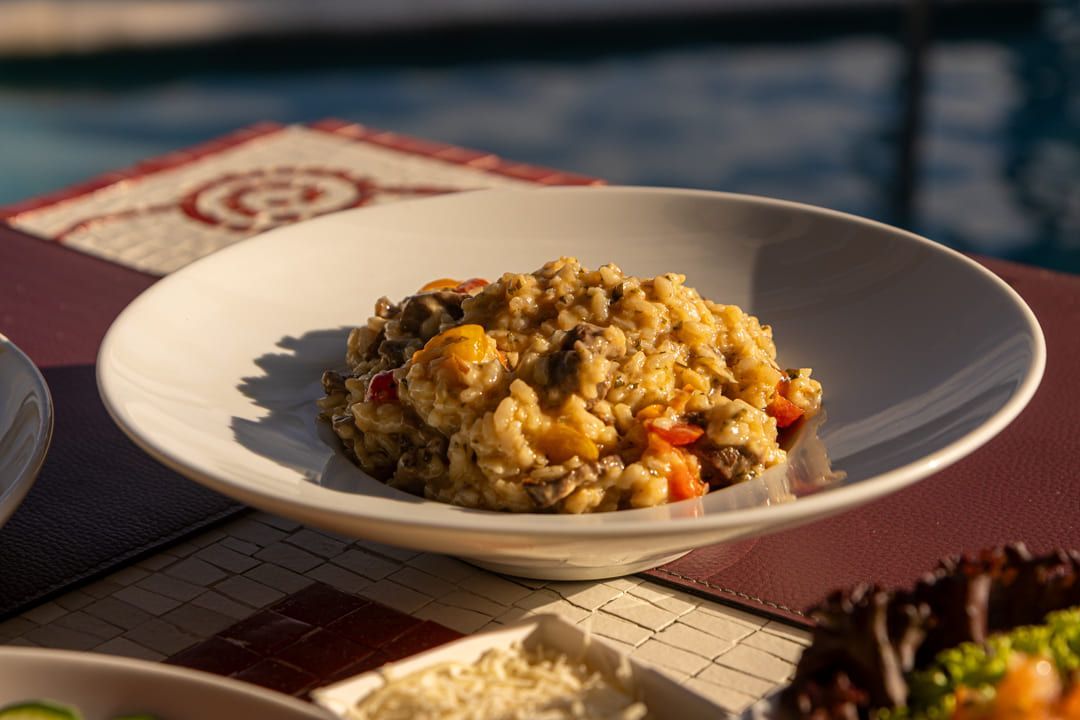 Uma tigela de comida está sobre uma mesa ao lado de uma piscina.