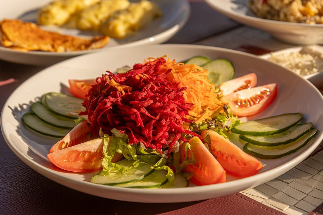 Um prato branco coberto com uma salada de tomates, pepinos e beterrabas.