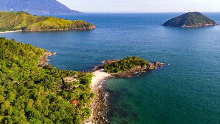 Uma vista aérea de uma praia com montanhas ao fundo.
