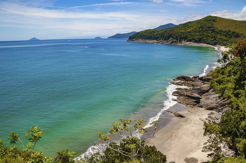 Uma vista aérea de uma praia com montanhas ao fundo.