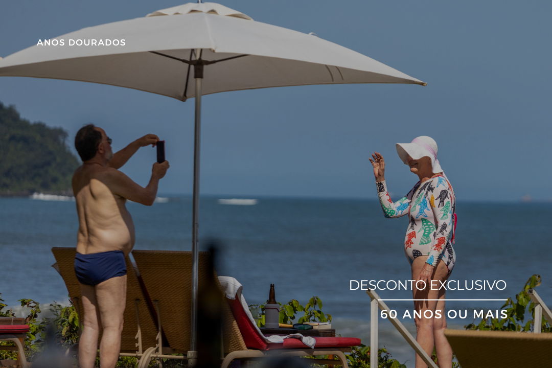 Hóspedes relaxando sob guarda-sol pé na areia na praia do Amora Hotel Maresias