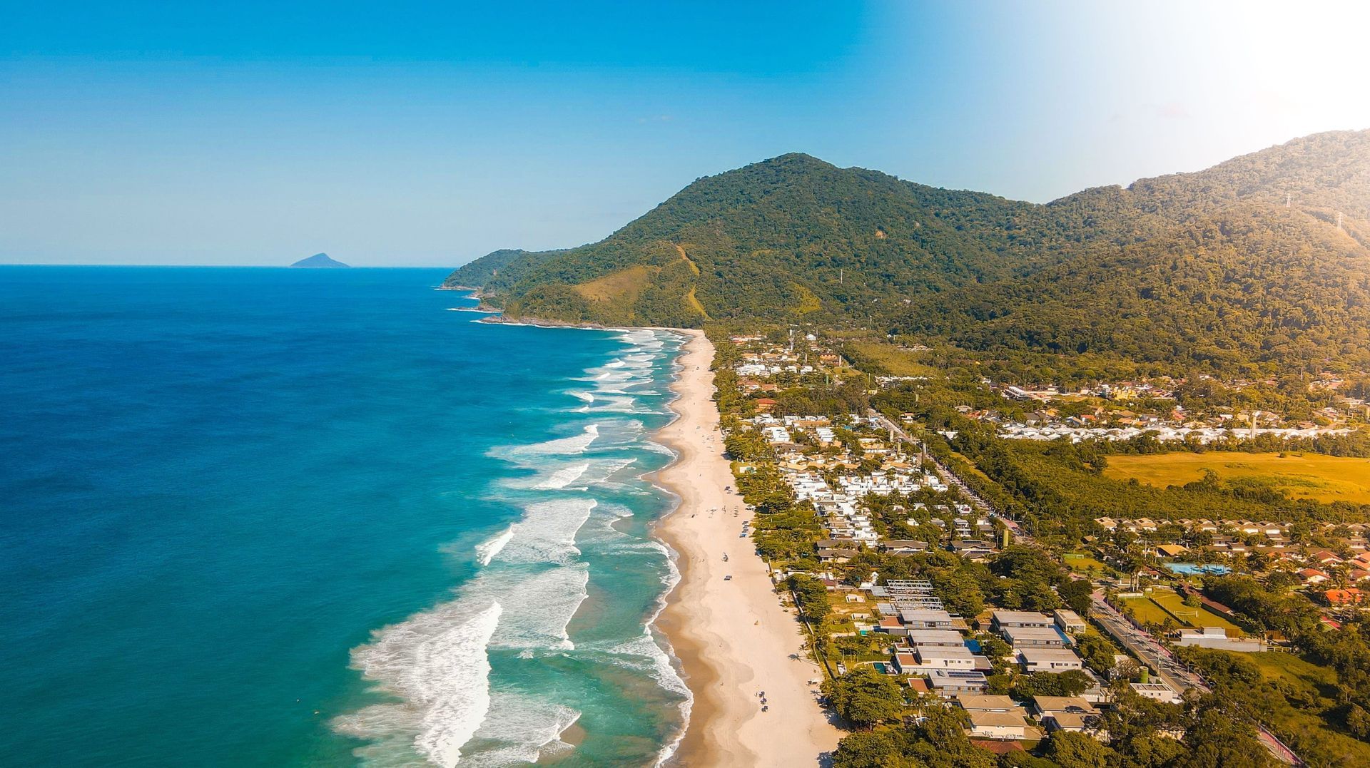 Uma vista aérea de uma praia com montanhas ao fundo.