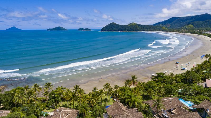 Uma vista aérea de uma praia com montanhas ao fundo.