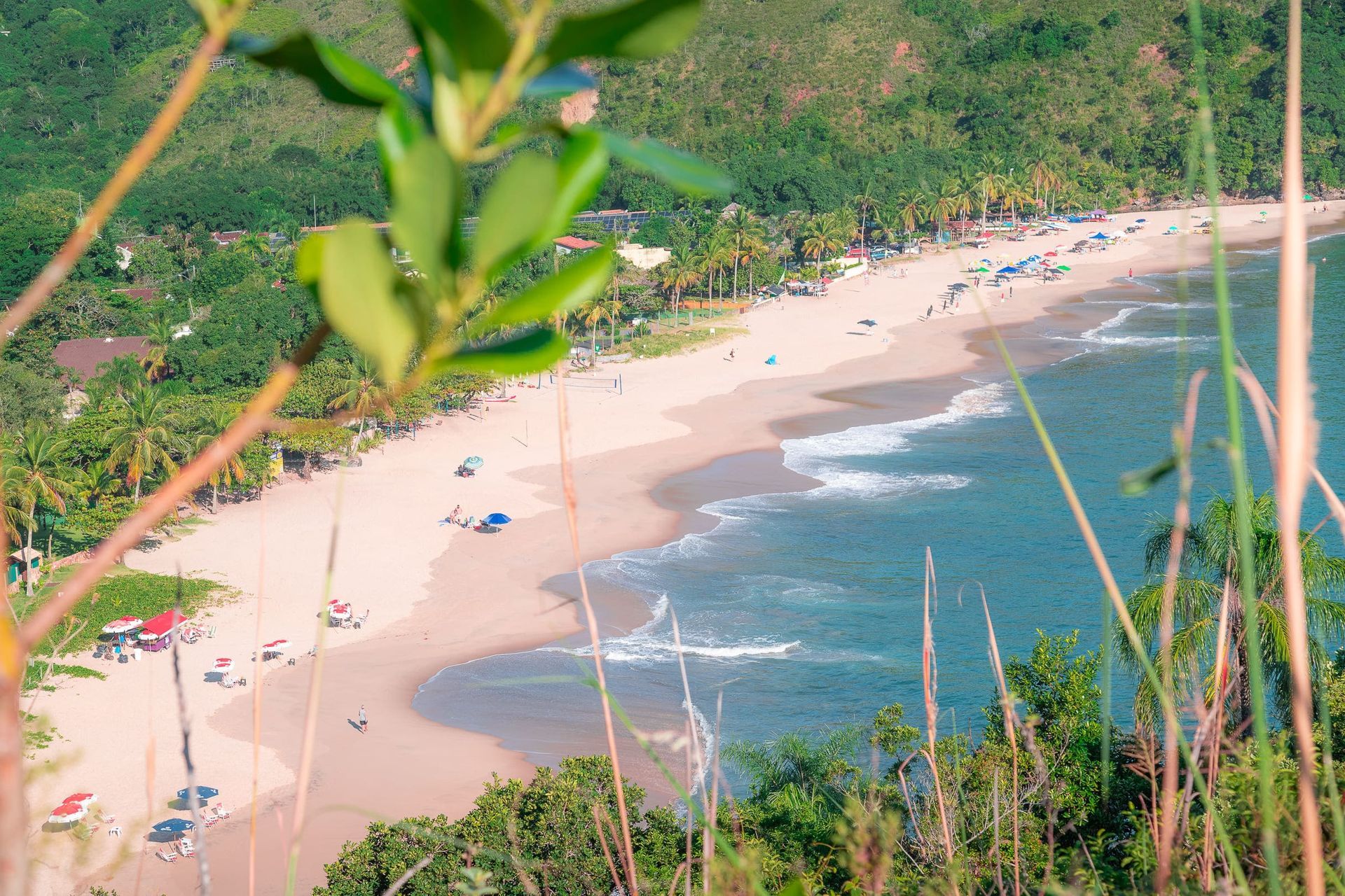 Uma vista aérea de uma praia com montanhas ao fundo.