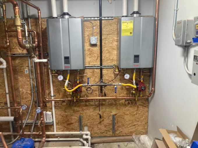 Mechanical room with wall-mounted boilers, exposed pipes, and utility equipment on plywood walls