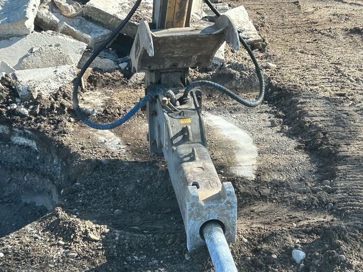 A concrete breaker is sitting on top of a pile of dirt.