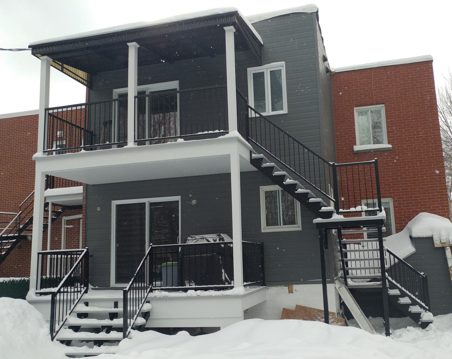 Une maison avec un balcon et des escaliers dans la neige