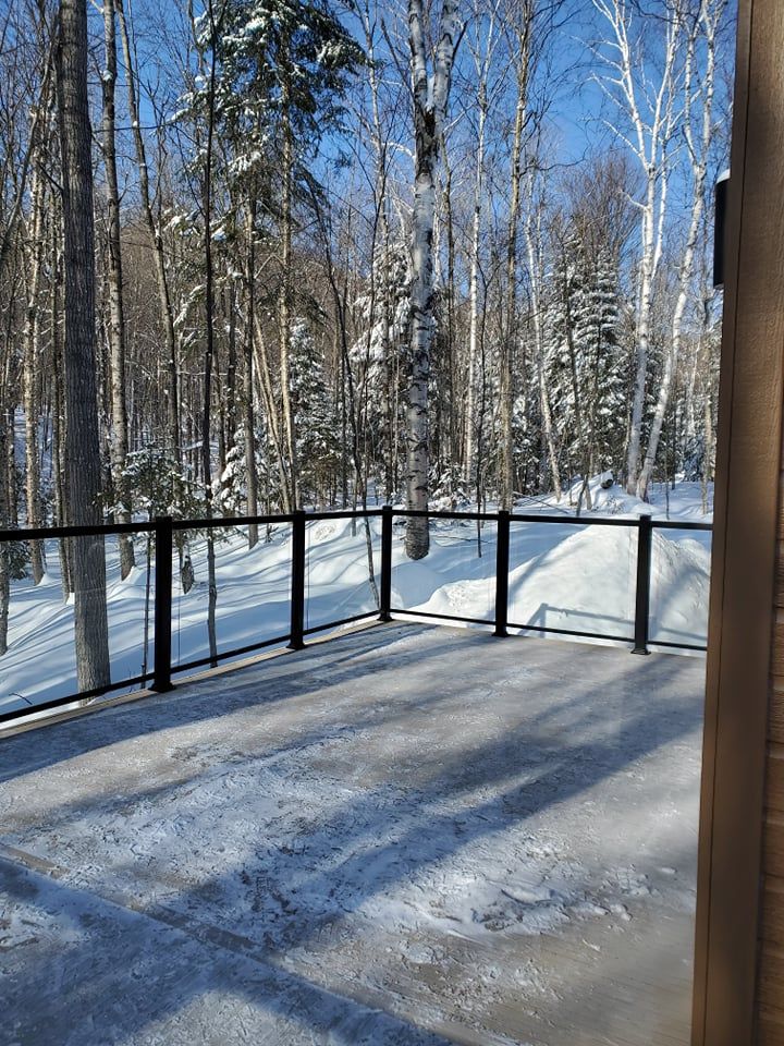 Une terrasse avec une balustrade donnant sur une forêt enneigée.
