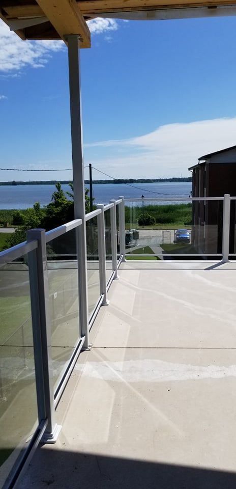 Un balcon avec une balustrade en verre donnant sur un plan d'eau.