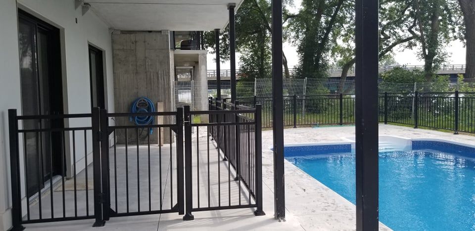 Une clôture entoure une piscine dans une cour arrière.