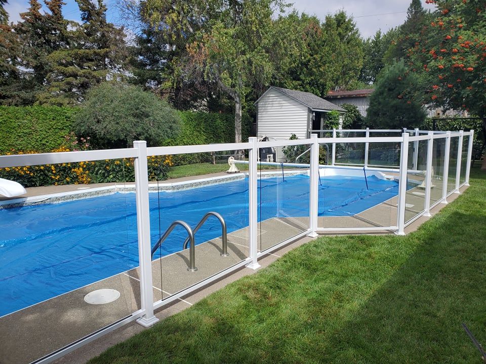 Une piscine entourée d'une clôture blanche.